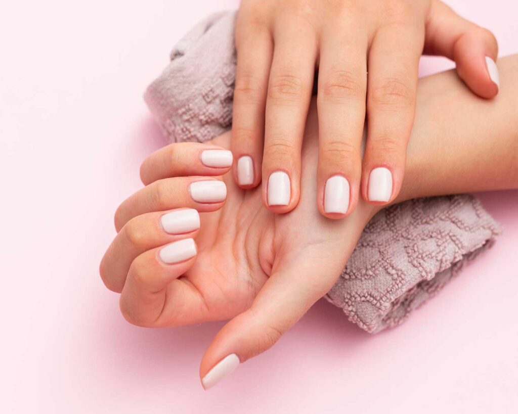 Manos de mujer con Manicure hecha en peluquería barbería